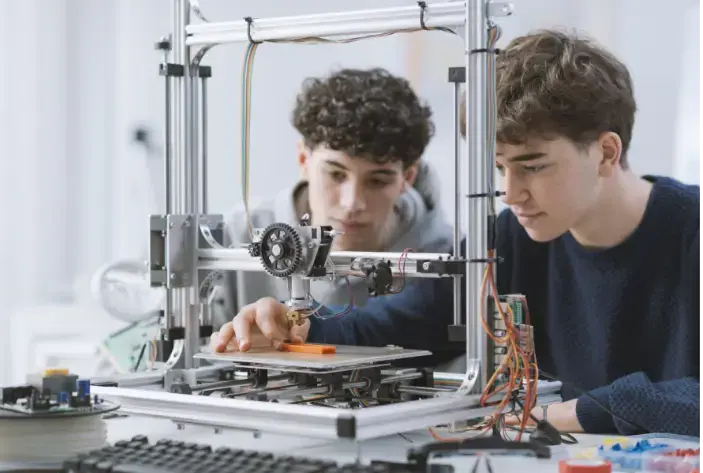 2 students working on a 3d printer